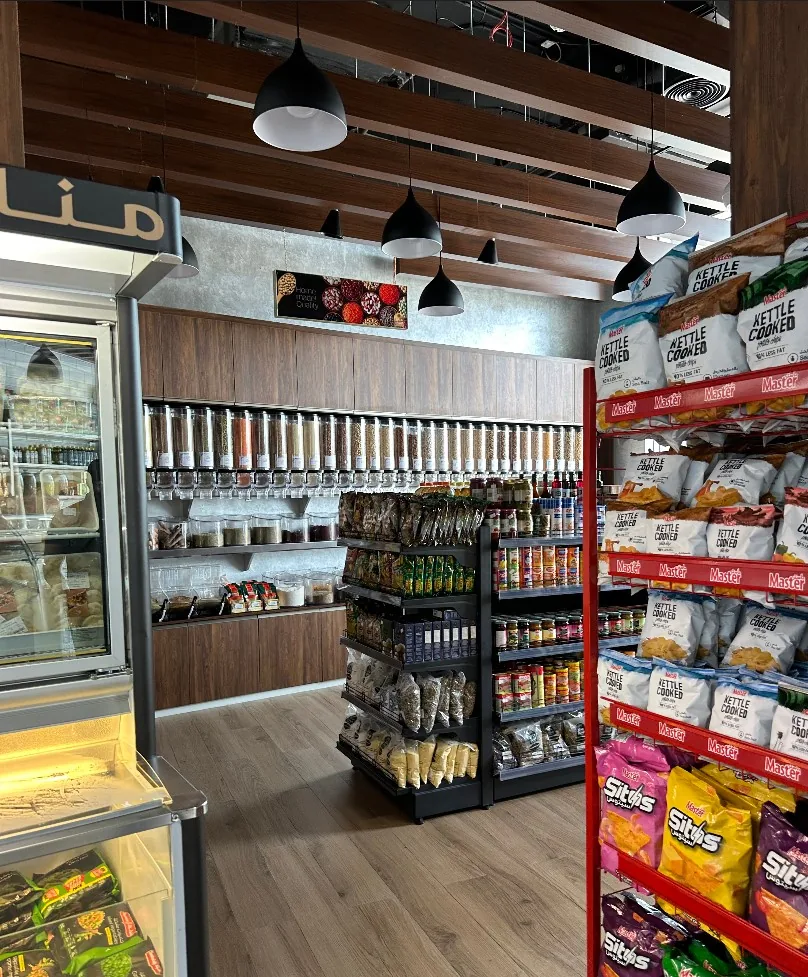 Inside a Manazel Al-Sham store, with bulk nut and spice dispensers, packaged groceries and chilled display cabinets